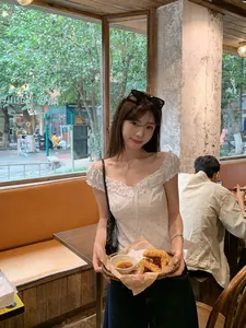 White floral milkmaid top with ruffled neckline and short sleeves in cafe setting