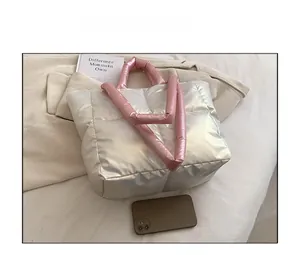 Detail view of the silver puffer tote bag with pink handles shown for size comparison