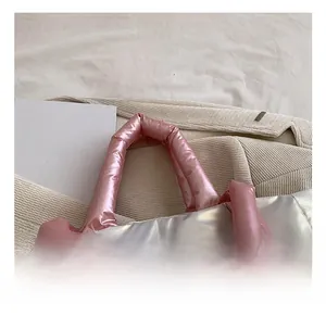 Close-up detail of metallic padded handbag handle in soft pink and shiny silver finish