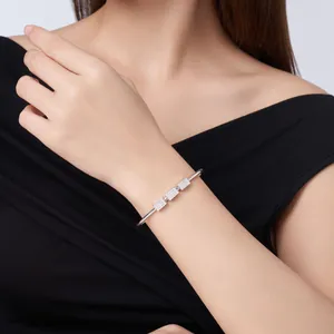 Close-up of elegant silver Moissanite bangle with three square pavé-set elements on wrist.