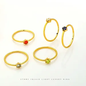 Close-up of five minimalist gold stainless steel rings with colorful round zircon stones.