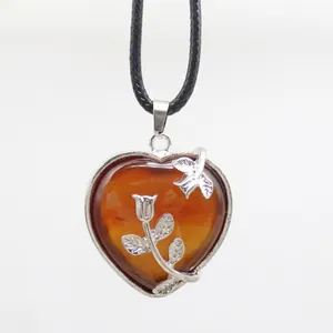 Close-up of heart-shaped brown stone pendant with silver rose flower detail