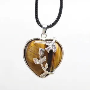Close-up of heart-shaped tiger's eye pendant featuring an intricate silver rose overlay