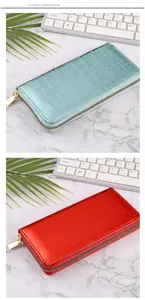 Detail of women's long wallets in teal and red with shiny crocodile pattern finish.