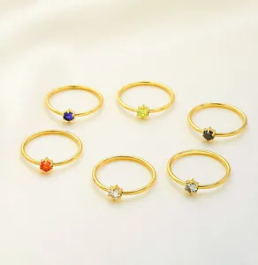 Detail showing a set of six gold-plated stainless steel rings with multi-colored zircons