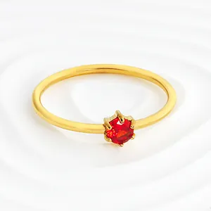 Macro view of a gold stainless steel ring with a brilliant red round cubic zirconia