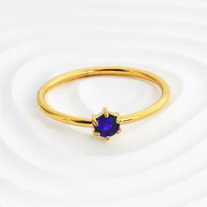Close-up detail of a minimalist gold stainless steel ring featuring a round purple zircon.