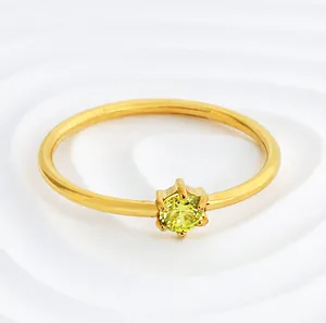 Macro detail showing the six-prong setting of a gold stainless steel ring with yellow zircon