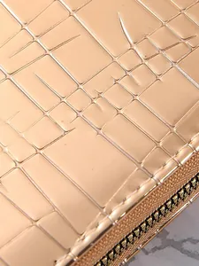 Close-up of a shiny rose gold women's long wallet with stone pattern texture and zipper.