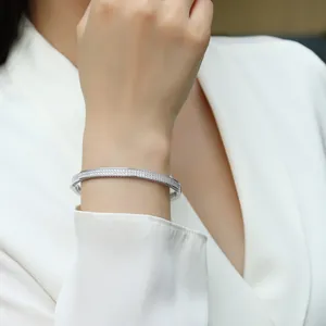 Elegant sterling silver moissanite bangle bracelet on female wrist with white blazer