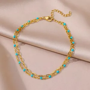 Detail view of a golden stainless steel double-layer anklet with blue evil eye beads.