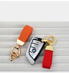 Goat grain leather car keychains in orange and red presented with a car key on a grey tray