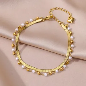 Detail view of a luxury golden stainless steel anklet with pearls and heart charm