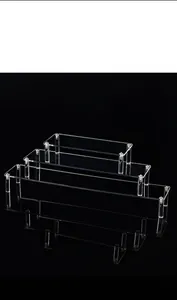 Detailed view of a 3-tier clear acrylic display stand on black reflective surface