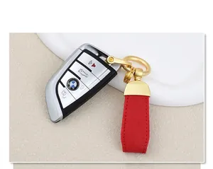 Close-up of red goat-grain leather keychain with golden horseshoe buckle and car key fob