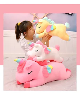 Assorted soft unicorn plush toys in yellow, white, and pink held by a young woman