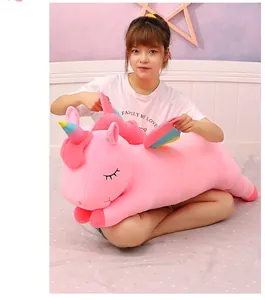 Soft pink unicorn plush toy being held by a girl to show its large size and fluffy texture.