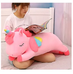 Soft pink unicorn plush toy held by a model in a cozy bedroom setting detail