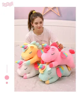 Detailed view of multiple colorful and soft unicorn plush toys held by an Asian model
