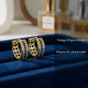 Detail view of gold hoop earrings with blue and white stones and heart filigree