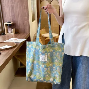 Détail d'un sac cabas en toile fleurie avec imprimé plumes de paon dans un café confortable.