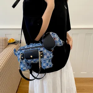 Detailed view of a puppy-shaped crossbody bag made of blue distressed denim fabric.