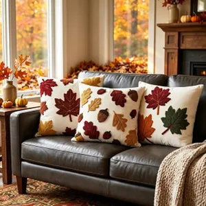 Detail of autumn embroidered pillowcases with maple leaf and acorn designs on sofa