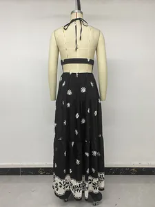 Back view of a black halter neck backless maxi dress with white floral prints detail.