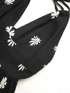 Detailed macro view of black halter neck dress featuring elegant white floral print patterns