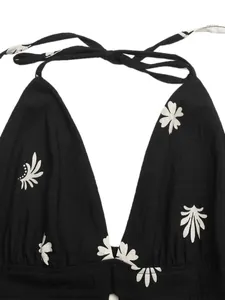 Close-up detail of a backless halter neck dress with white floral print on black fabric
