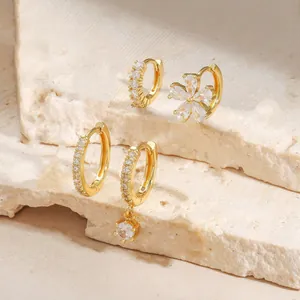 Elegant gold-plated earring set with flower pendant and zircon stones on stone background