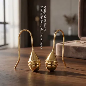 Close-up of sculptural gold drop earrings with textured teardrop design