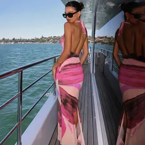 Sexy backless halter maxi dress with abstract pink print and high slit on a luxury yacht deck.