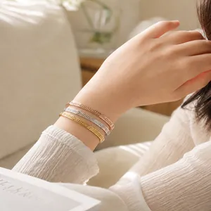 Close-up of three stacked Great Wall pattern titanium steel bangles on female wrist
