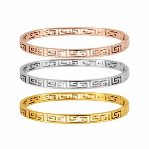 Macro view of three titanium steel bangles with hollow Greek key motifs in tri-color finishes