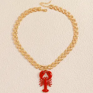 Close-up of elegant gold watch-strap chain necklace with a vibrant red lobster pendant