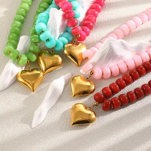 Dettaglio di collane di perle in resina colorata con pendenti a cuore dorati in vari colori