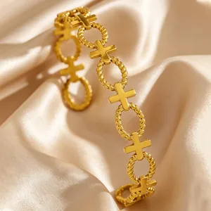 Close-up of vintage gold stainless steel bracelet with rope rings and cross links on silk