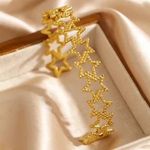 Detail of gold stainless steel star bangle with hollowed-out bohemian vintage design.