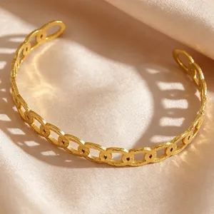 Close-up of vintage gold textured chain link cuff bracelet resting on champagne silk fabric