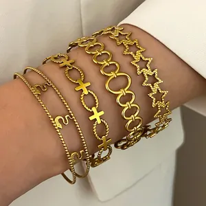 Detailed view of layered gold-plated stainless steel bracelets with star and cross charms