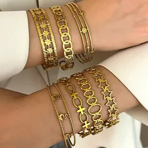 Close-up detail of various stacked golden stainless steel bracelets on model's arms