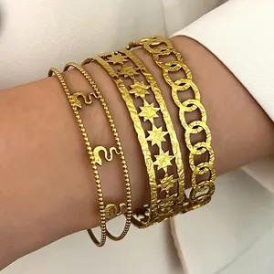 Detailed view of stacked vintage bohemian gold stainless steel bracelets on a female wrist