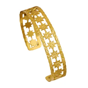 Close-up of vintage bohemian gold star cuff bracelet with textured hammered finish