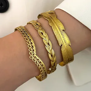 Macro detail of three gold stainless steel bracelets with feather and braided designs.