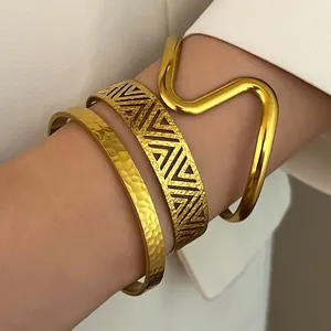Detailed macro shot of stacked vintage gold stainless steel cuff bracelets with textured patterns