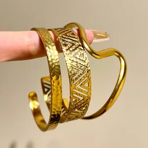 Detail of stacked gold bohemian stainless steel bangles with hammered and cutout patterns