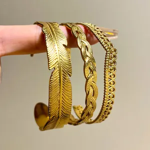 Close-up of three vintage gold stainless steel bangles with feather and braided patterns