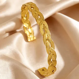 Detail of a vintage gold-plated stainless steel braided cuff bracelet on silk background.