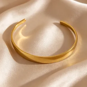 Detailed view of a minimalist gold-plated stainless steel cuff bracelet on silk